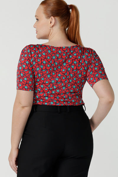 Back view size 12 woman wears the Ziggy top in Rio with a red base and seventies style floral. Round and conservative neckline. Short sleeve and made in Australia for women size 8 - 24.