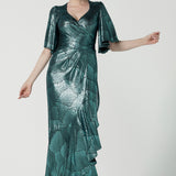 A size 10 woman wears the Zsa Zsa Maxi Dress in Green Mikado. Evening wear wrap dress with frill sleeves and ruffles made in metallic jersey. Made in Australia for women size 8-24.