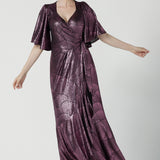 A size 10 woman wears a glamorous wrap dress for cocktail wear. Made in Australia wit pink foil mikado fabric with detailed design and flutter with with tears. Low neckline and flattering for all shapes petite to plus size ladies clothing. Made in Australia for women size 8 - 24.