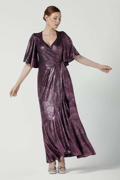 A size 10 woman wears a glamorous wrap dress for cocktail wear. Made in Australia wit pink foil mikado fabric with detailed design and flutter with with tears. Low neckline and flattering for all shapes petite to plus size ladies clothing. Made in Australia for women size 8 - 24.