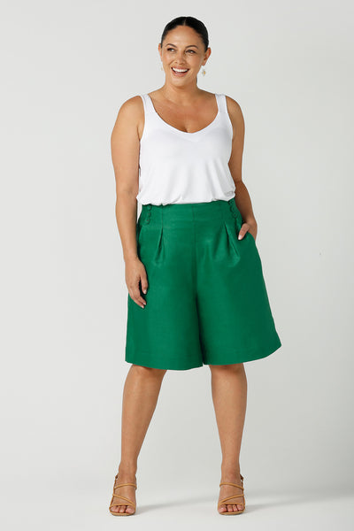 A size 12, curvy woman wears a tailored linen, long shorts in emerald green with a white bamboo jersey cami top - great for summer capsule wardrobes and travel wear! Both are made in Australia by Australian and New Zealand women's clothing brand, Leina & Fleur. 