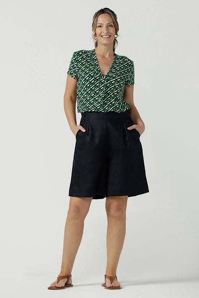A size 10, 40 plus woman wears tailored linen, bermuda shorts in midnight blue with a short sleeve, V-neck top in printed jersey - great for summer, travel capsule wardrobes and seasonal workwear! Both are made in Australia by Australian and New Zealand women's clothing brand, Leina & Fleur.