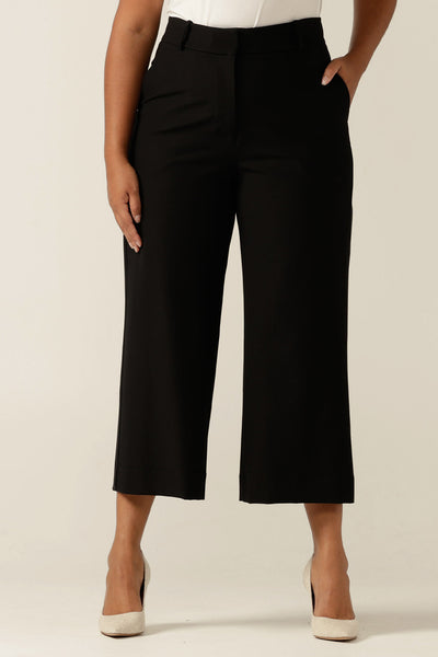 Size 12 woman wearing tailored wide leg, cropped-length, black work trousers, made in Australia, for a work wear style.