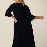 Back view of an elegant occasion wear, wrap dress with romantic fluted sleeves.