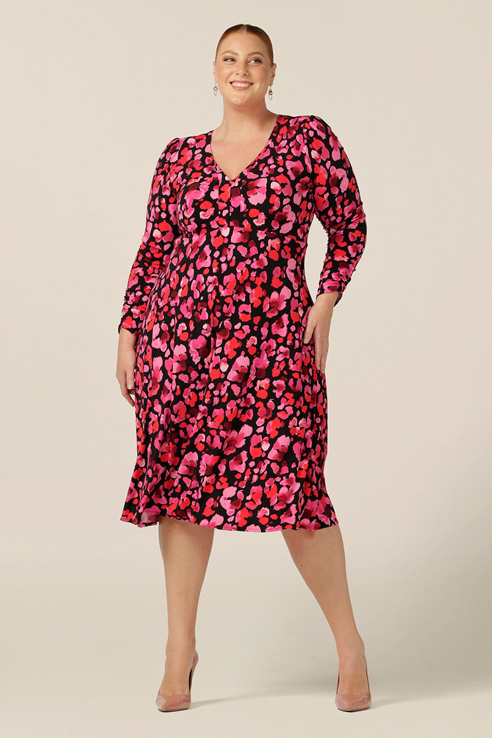 A plus size, size 18 woman wears a V-neck, empire line jersey dress with long sleeves. Made in Australia by Australia and New Zealand women's clothing label, Leina and Fleur. 