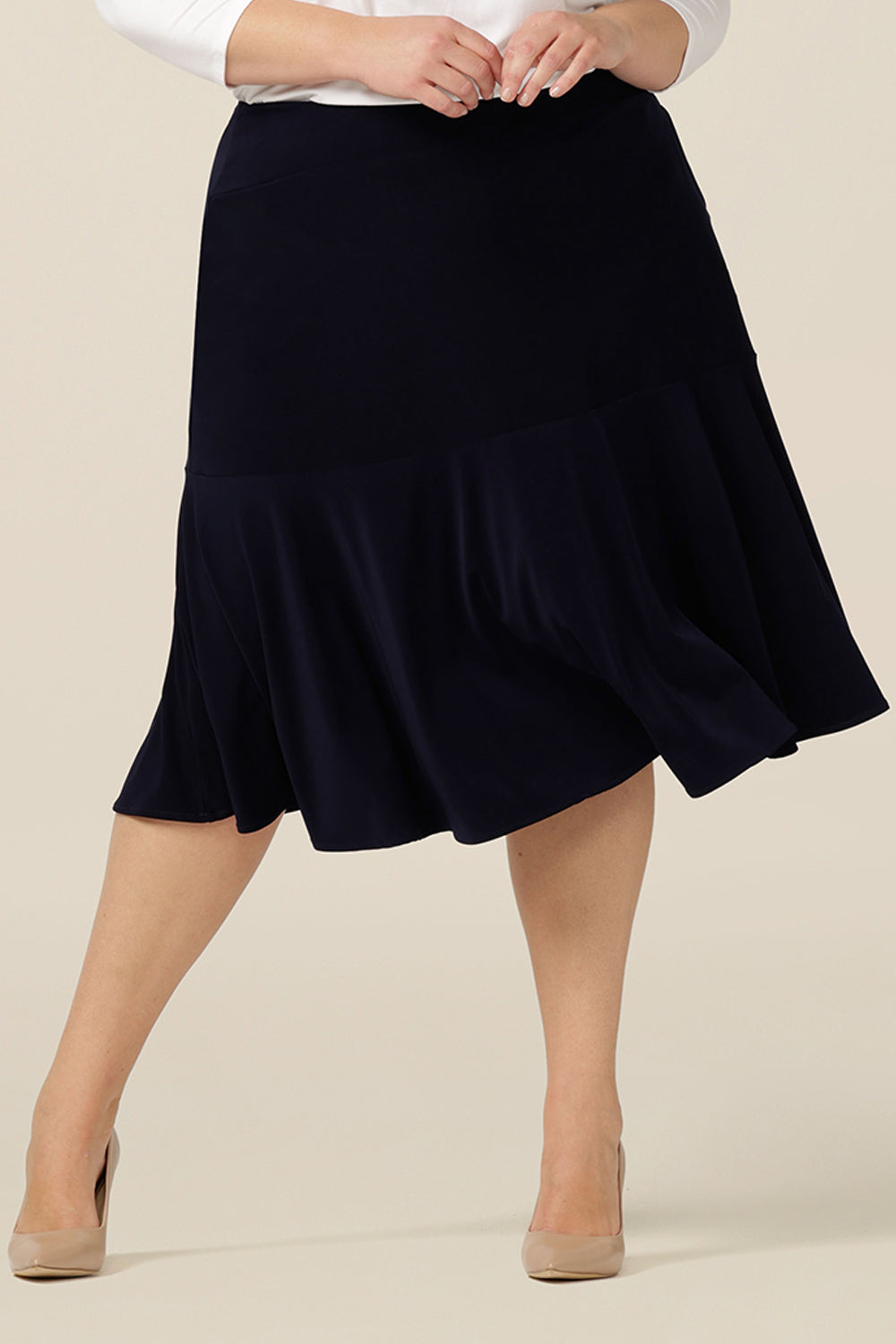 A navy blue, below-the-knee-length skirt with ruffle hemline. A pull-on skirt in stretch jersey fabric, this is a comfortable skirt for all-day work wear.