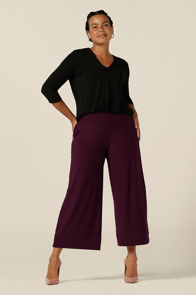 A size 12 woman wears wide leg pants in Mulberry jersey fabric by Australian and New Zealand women's clothing brand, L&F. Great workwear trousers, these pants feature a pull-on waist, pockets and cropped, ankle length legs.