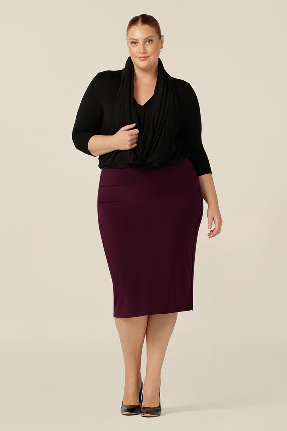 Made in Australia, this complete outfit showcases work wear for curvy women. Wearing a knee length tube skirt in Mulberry stretch jersey, black long sleeve top and black scarf, this size 18 woman layers up her work wear for a complete corporate wardrobe.