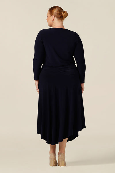 Back view of a good workwear skirt and top combination by Australian and New Zealand women's clothing company, L&F. Creating a faux dress look for work and event wear, a long sleeve, boat neck top in navy blue stretch jersey is worn with a navy skirt with asymmetric hemline.