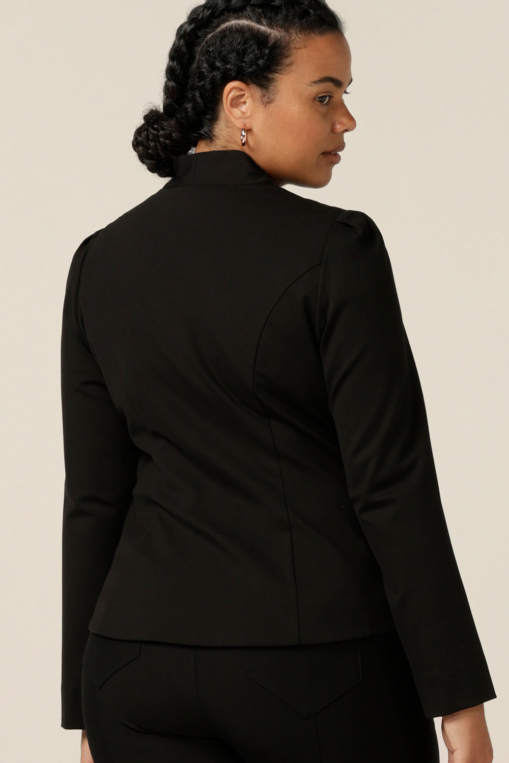 Back view of a size 12, curvy woman wearing a soft tailored black jacket with black workwear pants. Made in Australia for petite to plus sizes, the stretch ponte jersey jacket is well-fitting on womanly curves.