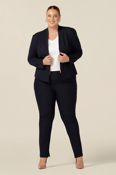 Styled as a corporate wear outfit, this navy collarless jacket with rose gold zip fastening is worn with slim leg, navy trousers and a white bamboo jersey top. Perfect work wear for plus size and fuller figure women, this jacket is worn by a size 18 woman and comes in sizes 8 to 24.
