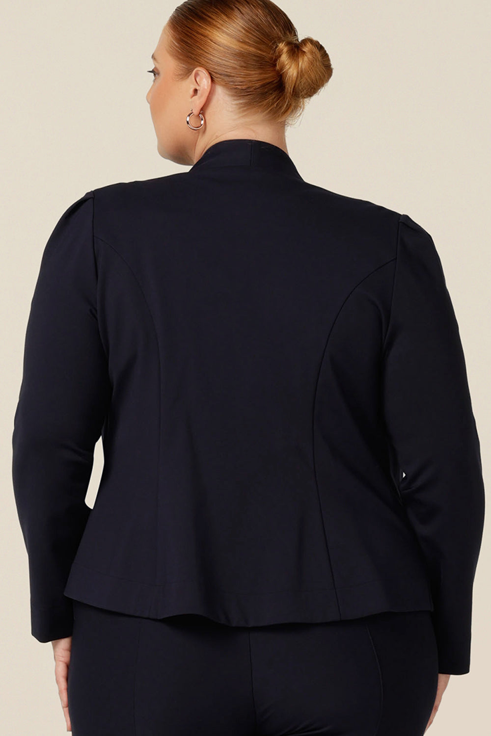 Back view of a size 18, fuller figure woman wearing a soft tailored navy jacket with navy work wear pants. Made in Australia for petite to plus sizes, the stretch ponte jersey is well-fitting on womanly curves.