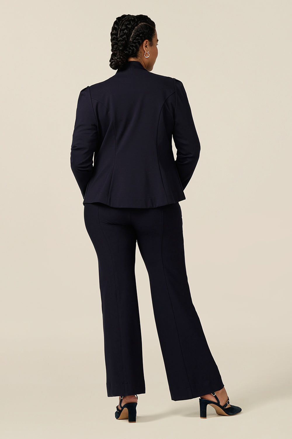 Back view of a size 12, curvy woman wearing a soft tailored navy jacket with navy workwear pants. Made in Australia for petite to plus sizes, the stretch ponte jersey jacket is well-fitting on womanly curves.