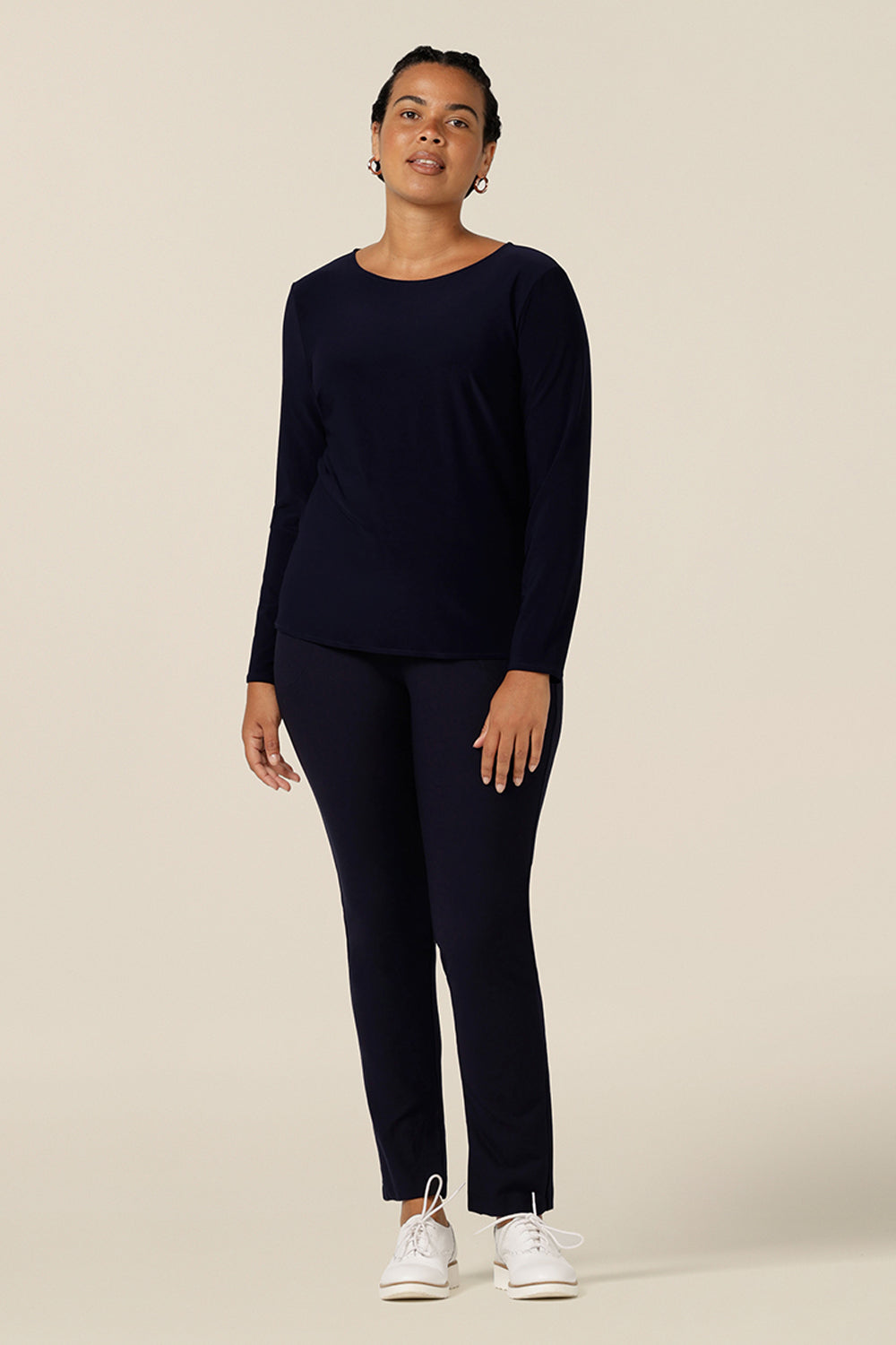 a size 12, curvy woman wears boat neck jersey top in navy blue. A good capsule wardrobe basic, this long sleeve jersey top is worn with slim leg navy blue pants for a casual outfit.