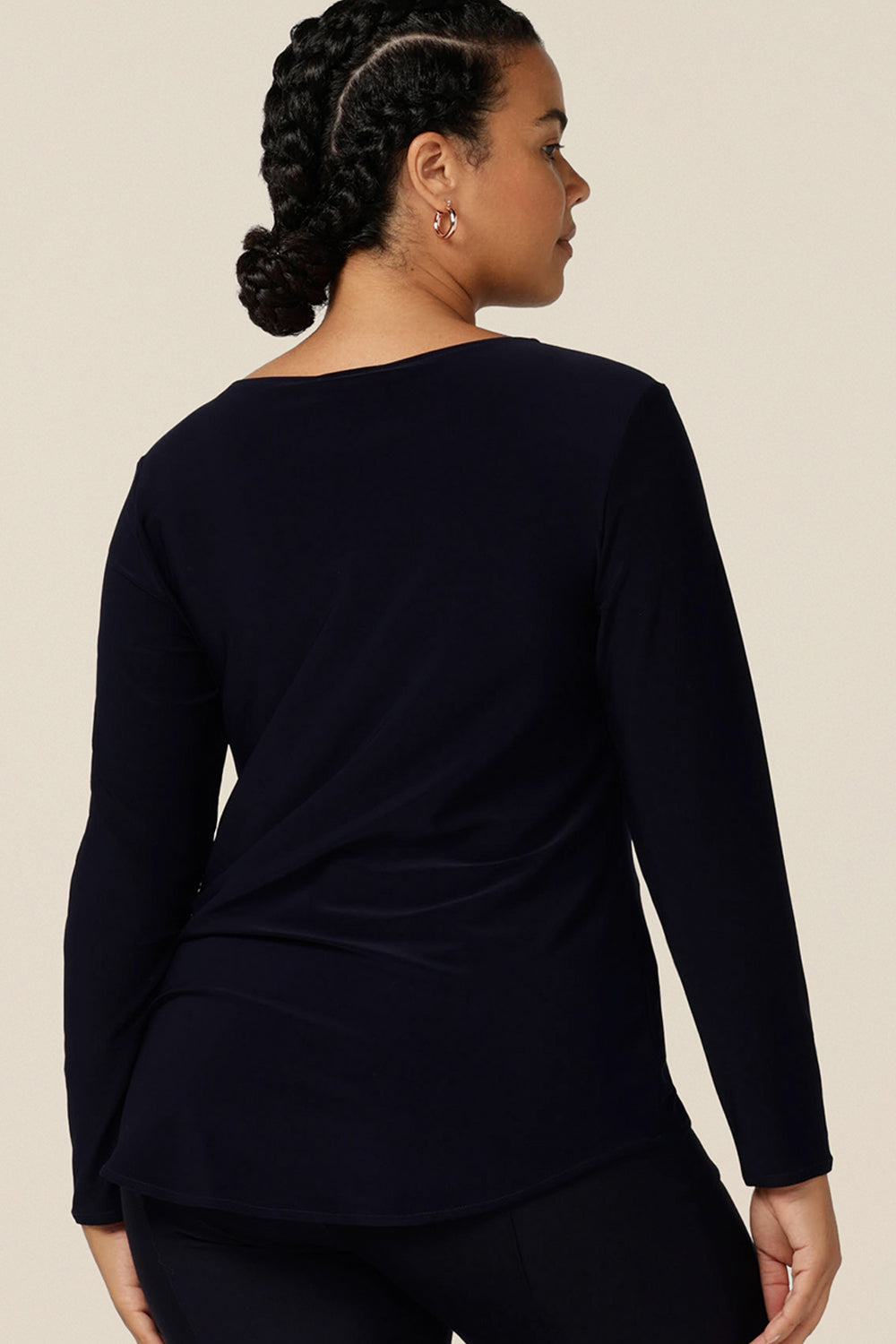 back view of a size 12, curvy woman wearing a boat neck jersey top in navy blue. A good capsule wardrobe basic, this long sleeve navy top is easy to wear for casual or work wear style.