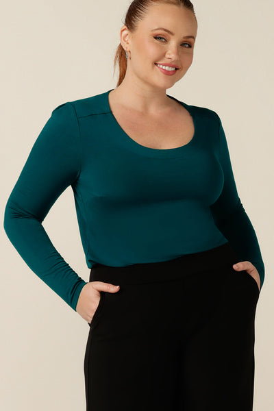 a size 12, curvy woman wears a round neck, long sleeve, fitted top in green bamboo jersey. In natural fibres, the bamboo jersey top is lightweight, breathable and comfortable for corporate or casual wear.