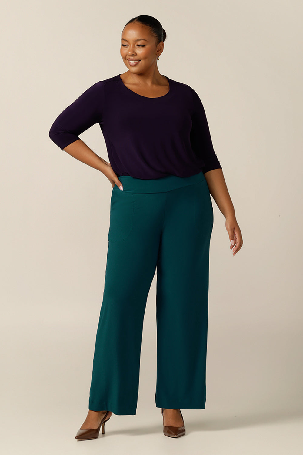 A plus size 18 woman wears Petrol green, straight cut, wide leg, full-length, pull on pants by Australian and New Zealand women's clothing brand, L&F. Featuring a pull-on waistband, these stretch jersey trousers are good pants for comfortable corporate wear. 
