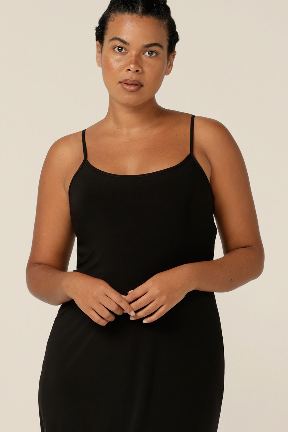 Plus size lounge wear - plus size slip dress - plus size strap dress -Close up of a scoop neckline on a reversible black slip in size 12.  The calf-length slip is made in Australia and layers under dresses and separates. The black slip has thin straps and is worn with a scoop neck to the front.