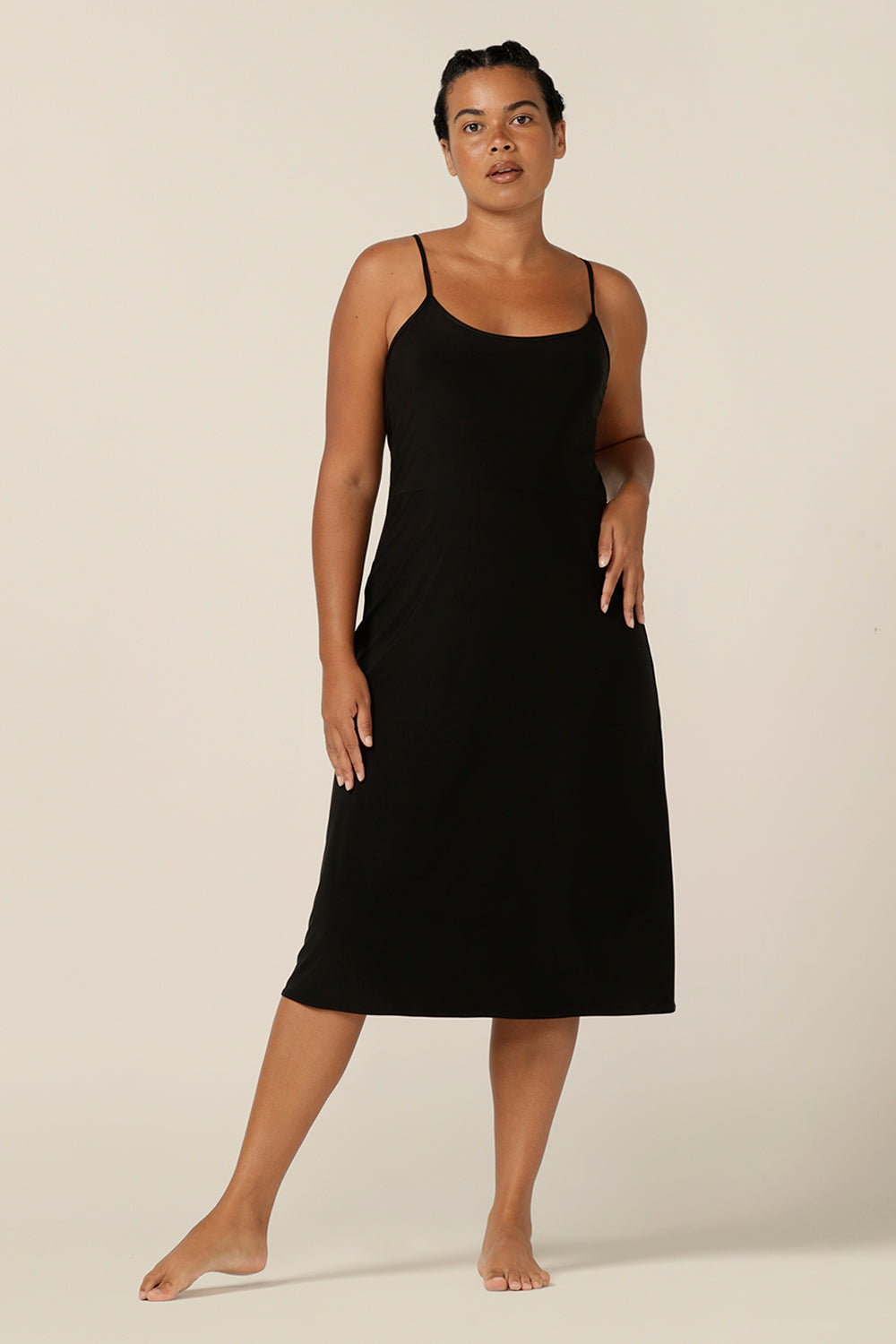 size 12 woman wears a midi-length, reversible slip in black, slinky jersey fabric. The slip has thin straps and is worn with a scoop neck to the front.