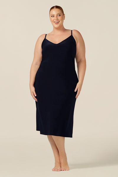 A fuller figure woman wears a midi-length, reversible slip in navy stretch jersey. Worn with a V neck to the front, this slip can flip to show a scoop neck. With a skirt length finishing below the knee, this midi slip gives a smooth layer under dresses and skirts.