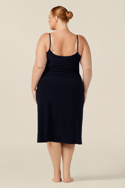 A fuller figure woman wears a midi-length, reversible slip in navy stretch jersey. Worn with a V neck to the front, and scoop neck to the back. With a skirt length finishing below the knee, this midi slip gives a smooth layer under dresses and skirts.