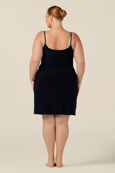 plus size slip dress - back view of a fuller figure, size 18 woman wears a navy, mini-length slip. A reversible slip, this undergarment can have a V-neck or a scoop neck to give a smooth layer under dresses and skirts.