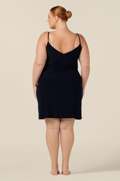 lounge wear for curvy women - Back view of a plus size, size 18 woman wears a navy, mini-length slip. A reversible slip, this under garment can have a V-neck or a scoop neck to give a smooth layer under dresses and skirts.