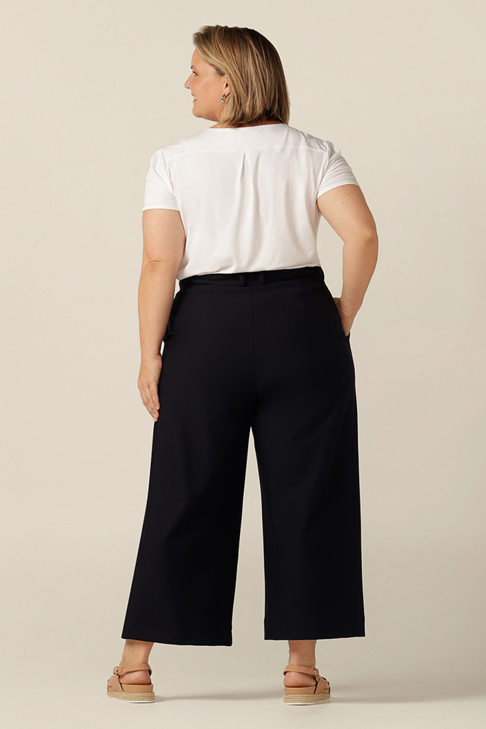 plus size woman wearing work-wear navy wide leg, cropped tailored pant with pockets styled with white bamboo jersey short-sleeve top 