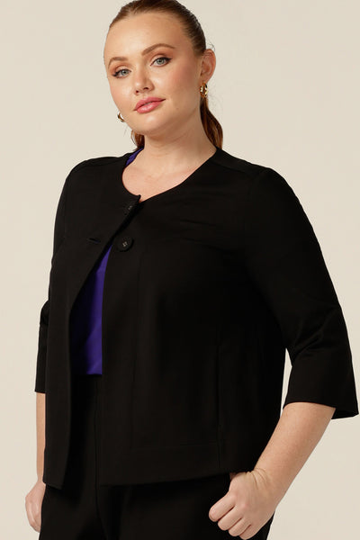 A curvy size 12 woman wears a black swing jacket for alternative corporate wear. Featuring round collarless neckline with 2-button fastenings, 3/4 sleeves and swing back, this black jacket has a sophisticated corporate elegance with made-in-Australia quality.