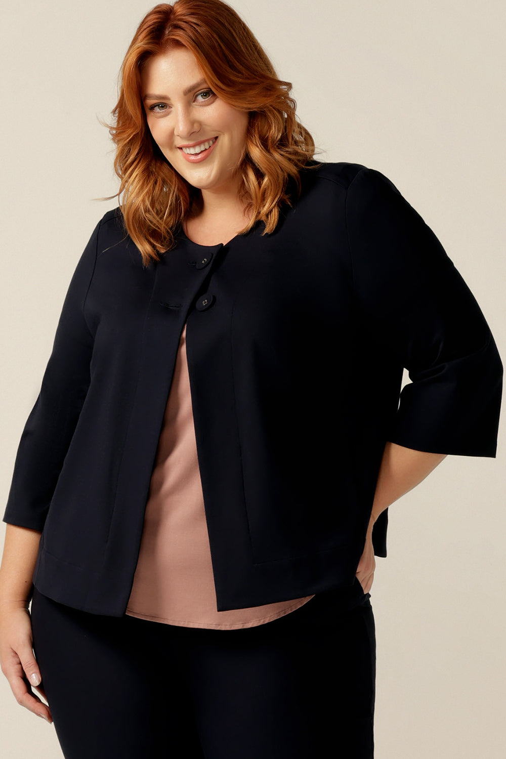 A plus size, size 18 woman wears a round neck navy work wear jacket with 3/4 sleeves